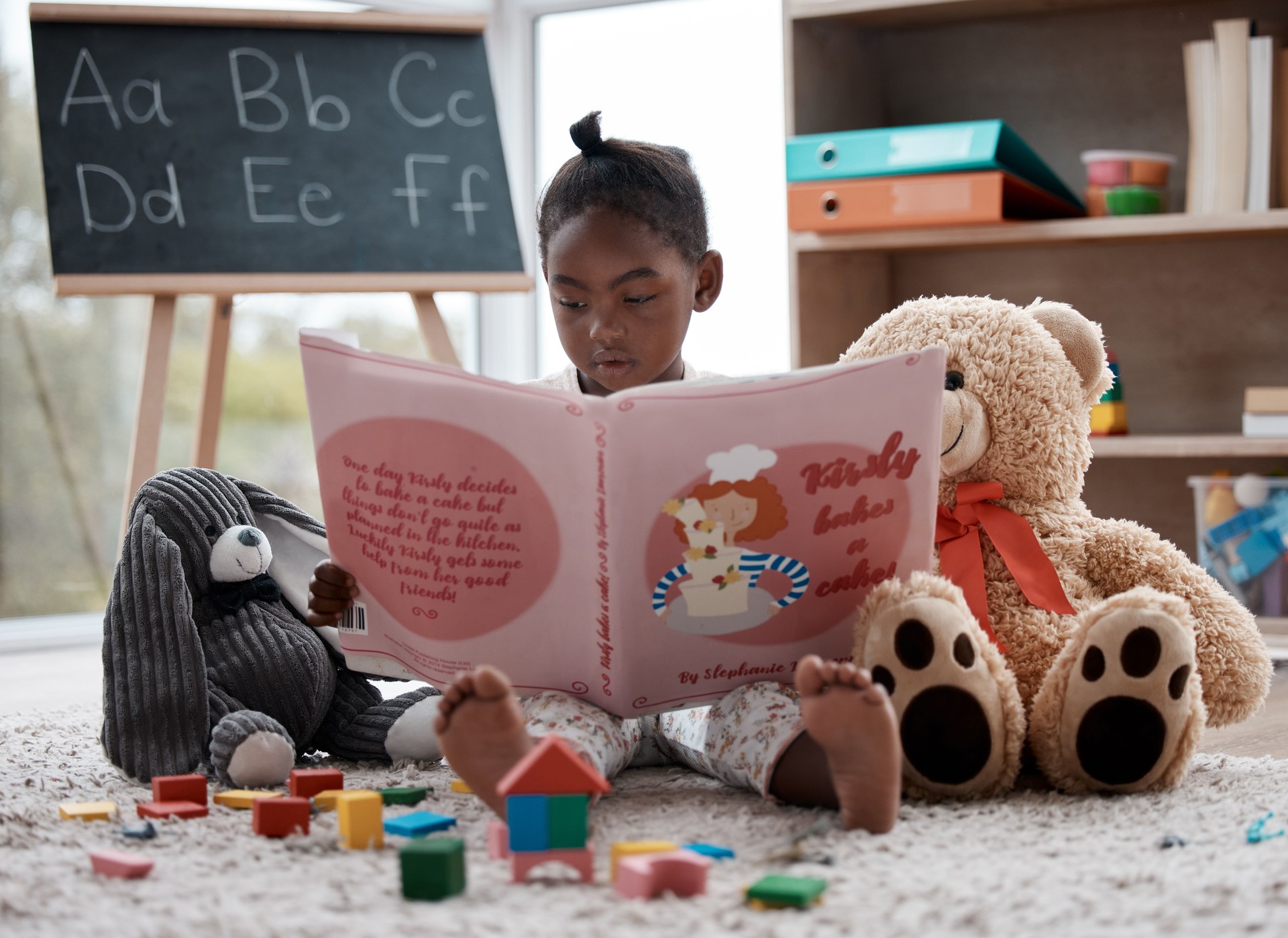 Shot of an adorable little girl reading a book while sitting at home